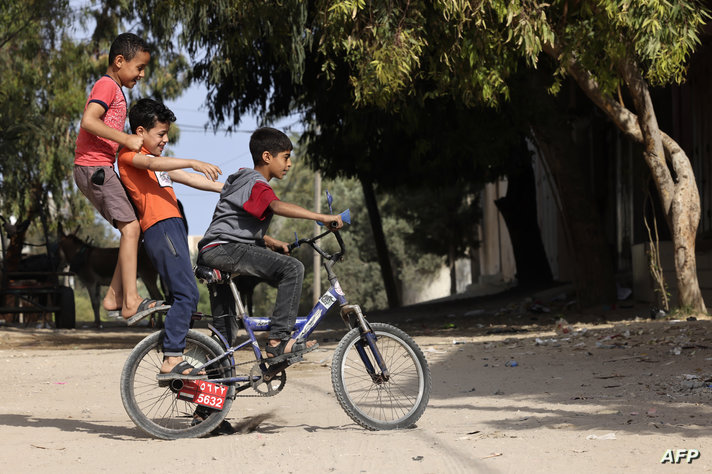 Children play on a bicycle at the Nusseirat refugee camp in Gaza, on May 14, 2023, amid a ceasefire ending five days of deadly…