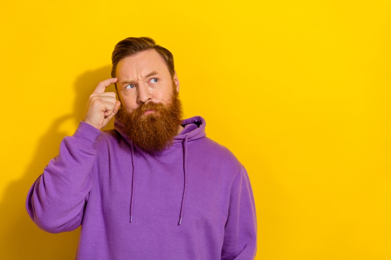 Photo of young serious handsome man can't remember look blank space brainstorming isolated on yellow color background.