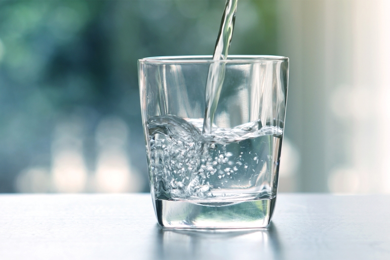 Close up pouring purified fresh drink water from the bottle on table in living room; Shutterstock ID 658012429; purchase_order: ajnet; job: ; client: ; other: