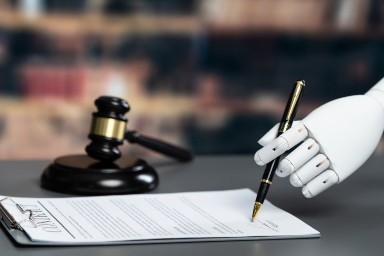 Future innovative concept of efficient and fair justice system with closeup robotic hand signing legal document as artificial intelligence in transparent judicial proceedings by AI judge. Equilibrium; Shutterstock ID 2287184085; purchase_order: aljazeera ; job: ; client: ; other: