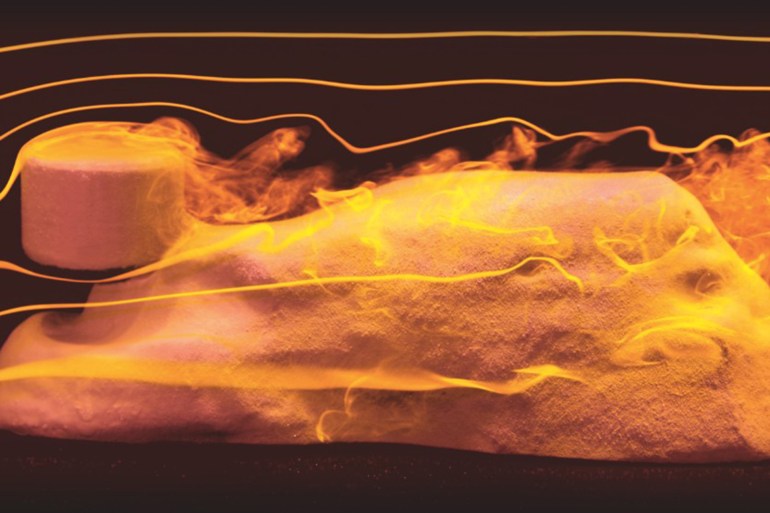 A lab Sphinx is carved through an experiment that replicates the wind moving against once-shapeless mounds of clay, with harder material becoming the “head” of the lion and other features—such as an undercut “neck,” “paws” laid out in front on the ground, and arched “back”—developing. Image courtesy of NYU's Applied Mathematics Laboratory.