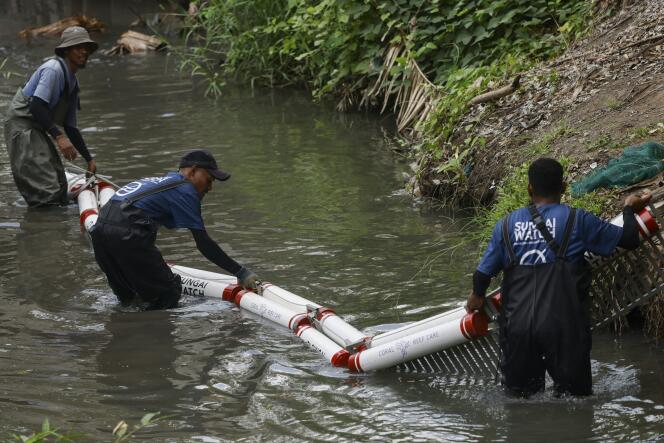 أعضاء جمعية Sungai Watch يقومون بتثبيت حاجز في نهر في منطقة كيروبوكان بجزيرة بالي الإندونيسية، 14 ديسمبر 2023.