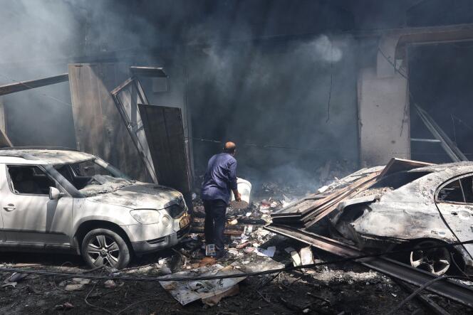 فلسطيني يستخدم دلوًا لإطفاء النيران في متجر مدمر في أحد المباني، في أعقاب عملية للقوات الخاصة الإسرائيلية في مخيم النصيرات وسط قطاع غزة في 8 يونيو 2024.