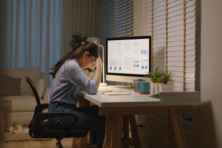 Asia people young woman study hard overnight brownout bored remote learn online read data tired sitting head in hands at home office desk workplace think worry in job tough stress workforce issue.; Shutterstock ID 2359115291; purchase_order: aljazeera ; job: ; client: ; other: