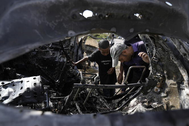 Des Palestiniens inspectent une voiture détruite par un drone dans le village de Zeita, au nord de la ville de Tulkarem, en Cisjordanie, le samedi 3 août 2024. L'armée israélienne déclare avoir frappé cinq terroristes présumés dans un véhicule alors qu'ils préparaient اعتداء.