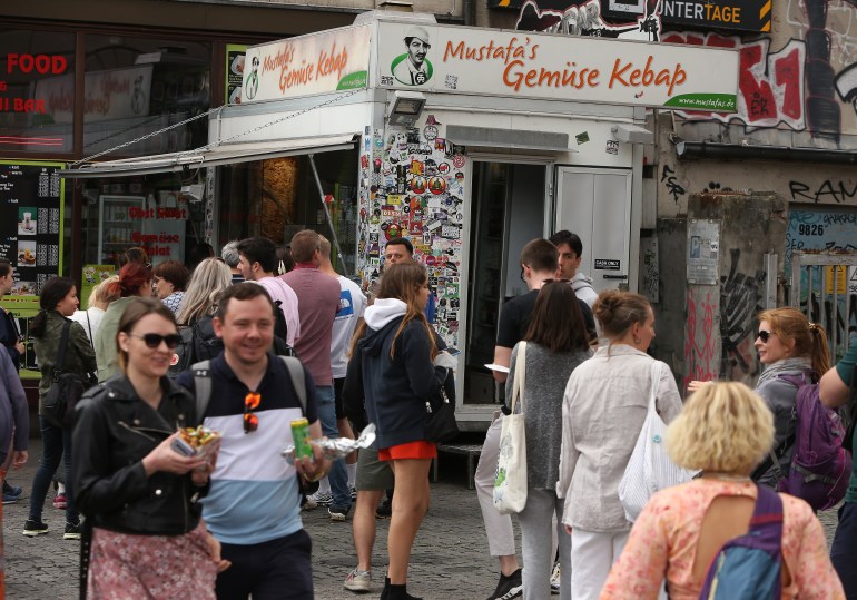 BERLIN, GERMANY - JULY 06: Visitors stand in line to order at Mustafas Gemüse Kebap on July 06, 2022 in Berlin, Germany. The döner kebab, a fast food sandwich made of stacked, seasoned meat turned on a rotisserie, was popularized in Germany in the early 1970s by Turkish guest workers (Gastarbeiter in German, or migrants arriving in Germany after World War II to counter labor shortages), with more stands offering the dish in Berlin than in Istanbul, and many considering it to be Germany's national dish. (Photo by Adam Berry/Getty Images)