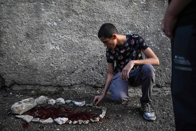 شاب فلسطيني يلاحظ بقع دماء محاطة بالحجارة في بلدة الزبابدة الصغيرة جنوب شرق جنين بالضفة الغربية، 30 أغسطس، 2024، بعد غارة للجيش الإسرائيلي.