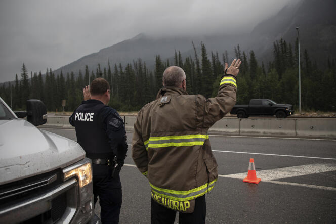 رئيس إطفاء هينتون ماك دي بودراب وضابط RCMP يرحبان بالمقيمين العائدين في جاسبر، ألتا، الجمعة 16 أغسطس 2024. 