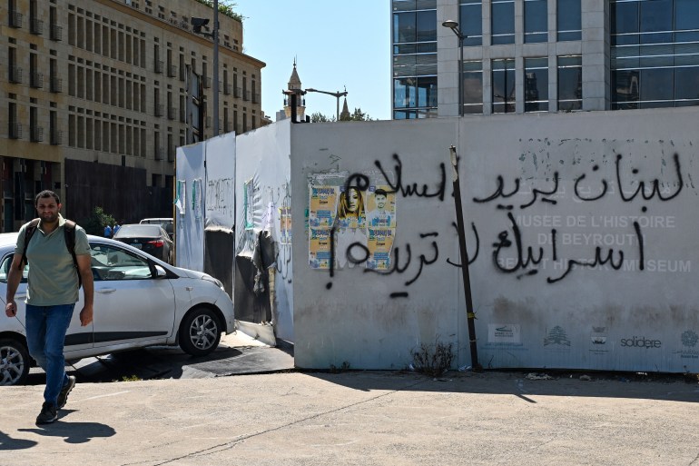 A Lebanese man walks past a graffiti that reads in Arabic: "Lebanon wants peace, Israel doesn't want it", at a street in downtown Beirut on August 2, 2024. (Photo by JOSEPH EID / AFP)