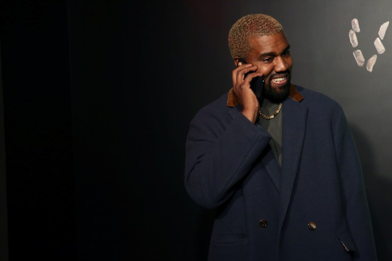 Rapper Kanye West talks on the phone before attending the Versace presentation in New York