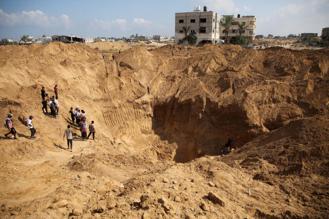 فلسطينيون يتجمعون لتفقد موقع حفرته القوات الإسرائيلية بعد انسحابها من المنطقة في أعقاب عملية برية، في خان يونس، جنوب قطاع غزة، 30 أغسطس، 2024. 