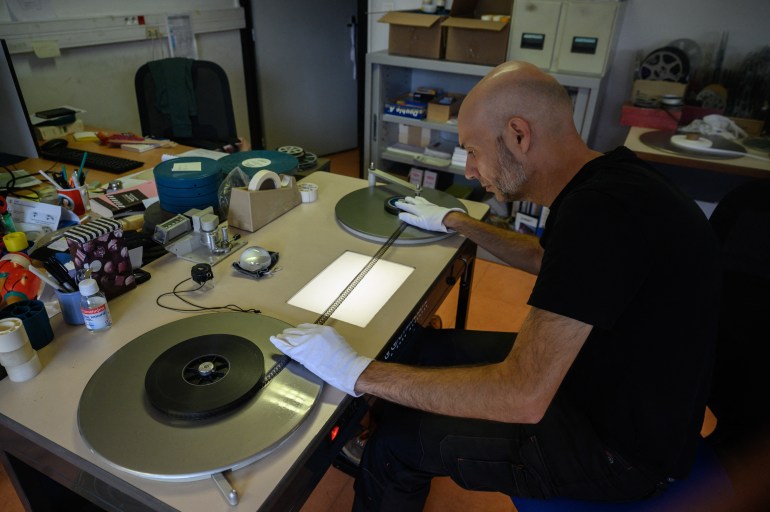 Archivist Matthieu Larroque inspects a reel of Palestinian film, part of a collection of 40 Palestinian films made between 1960 and 1980, at the Conservation and Research Center of the Toulouse Cinematheque, in Toulouse, southwestern France, on August 1, 2024. - In the early 1980s, the Palestinian Film Institute in Beirut, where around a hundred militant films were stored, was bombed by Israel during the Lebanon war. Its director, Khadijeh Habashneh, fled the country, leaving the reels behind. Almost 40 years later, the 79-year-old former director of the Institute has managed to collect 40 short and medium-length films, in 16 and 30 mm formats, which will be shown to the general public at the Cine Palestine festival in Toulouse. (Photo by Ed JONES / AFP)