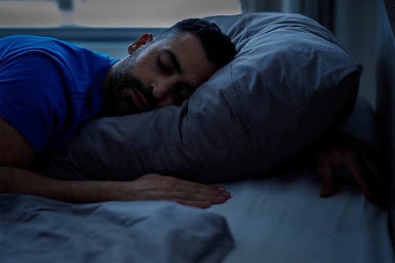 Sleeping young arab sleeping night, resting peacefully in a comfortable bed with gray linens with closed eyes, free space شترستوك