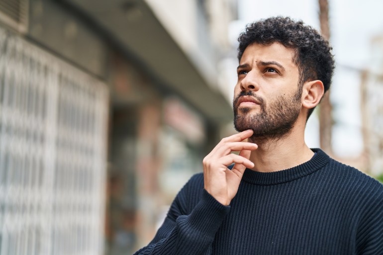 Young arab man standing with doubt expression at street