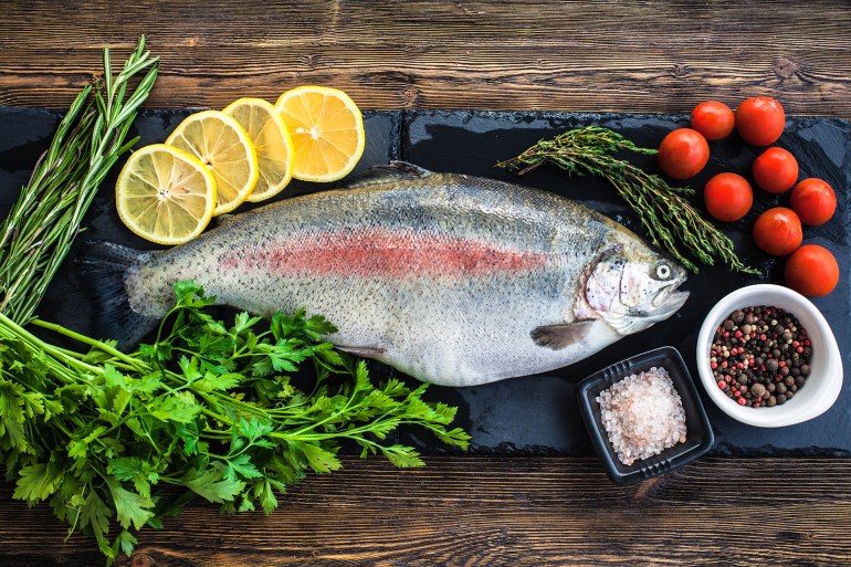 Big fresh salmon with greenery on the black board