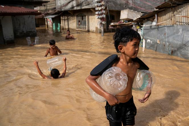 أطفال على طول شارع غمرته المياه بعد إعصار مان-يي الكبير، في كاباناتوان، نويفا إيسيجا، الفلبين، 18 نوفمبر 2024.