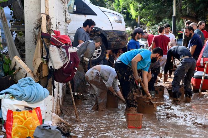 أشخاص يزيلون الطين من الشارع في 1 نوفمبر 2024 في ماساناسا بمنطقة فالنسيا بإسبانيا، بعد الفيضانات الرهيبة التي ضربت البلاد.