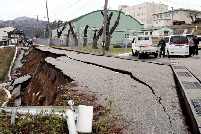 TOPSHOT - People stand next to large cracks in the pavement after evacuating into a street in the city of Wajima, Ishikawa prefecture on January 1, 2024, after a major 7.5 magnitude earthquake struck the Noto region in Ishikawa prefecture in the afternoon. Tsunami waves over a metre high hit central Japan on January 1 after a series of powerful earthquakes that damaged homes, closed highways and prompted authorities to urge people to run to higher ground. (Photo by Yusuke FUKUHARA / Yomiuri Shimbun / AFP) / NO USE AFTER JANUARY 30, 2024 16:00:00 GMT - JAPAN OUT / NO ARCHIVES - MANDATORY CREDIT: YOMIURI SHIMBUN - NO ARCHIVES - MANDATORY CREDIT: Yomiuri Shimbun