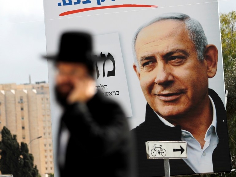 An ultra-Orthodox Jewish man walks in front a Likud party election campaign banner depicting Israeli Prime Minister Benjamin Netanyahu in Jerusalem March 1, 2020. REUTERS/Ammar Awad
