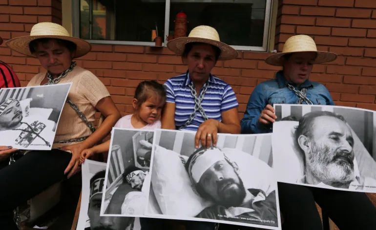 Relatives of five landless farmers, Felipe Balmori Benitez, Adalberto Castro, Nestor Castro, Arnaldo Quintana and Ruben Villalba – accused of causing riots that resulted in the deaths of six police officers and 11 farmers in June 2012 in what is now known as the Curuguaty massacre – protest outside a military hospital where the farmers were held, in Asuncion, on April 11, 2014 [Jorge Adorno/Reuters]