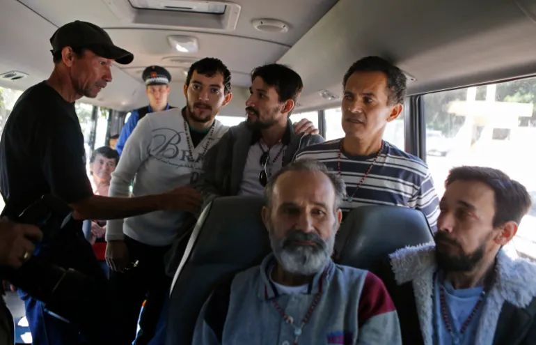 Paraguayan farmers (standing, from 2nd left) Adalberto Castro, Arnaldo Quintana, Ruben Villalba, (sitting, from left) Felipe Balmori Benitez and Nestor Castro, who were accused of causing land-related riots that resulted in the deaths of six police officers and 11 farmers in June 2012, sit in a bus after being released from the military hospital in Asuncion on April 15, 2014 [Jorge Adorno/Reuters]