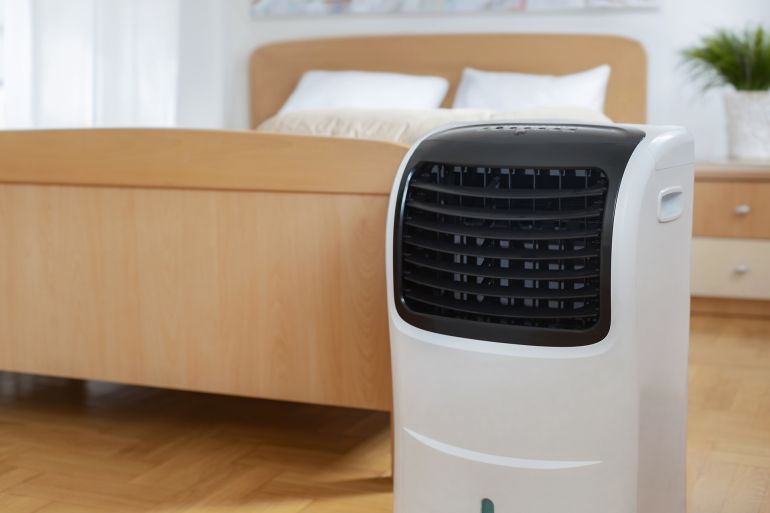 Portable mobile air conditioner stands in the bedroom at home, copy space