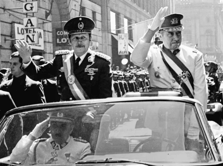 Military dictators Alfredo Stroessner (left) of Paraguay and Augusto Pinochet of Chile ride through the centre of Santiago during a state visit by Stroessner in September, 1974 [File: Reuters]