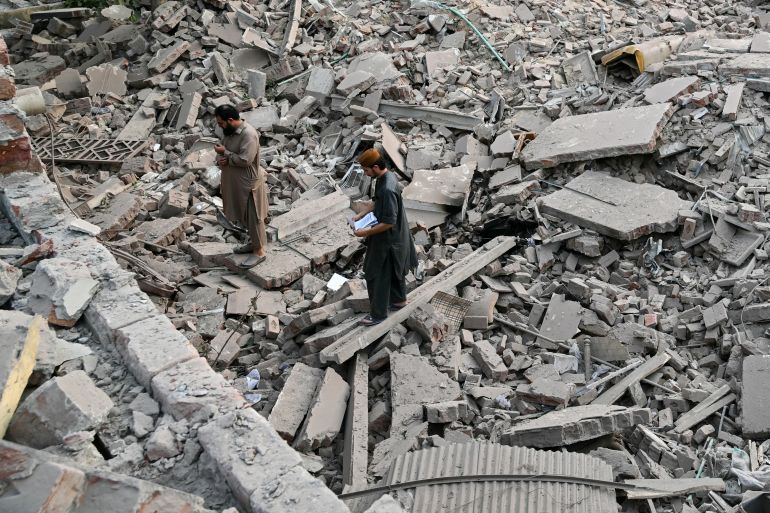 Locals stand on the debris of destroyed structures at the Government Health and Educational complex in Muridke about 30 kilometres from Lahore, on May 7, 2025, after Indian strikes. The death toll from Indian strikes on Pakistan has increased to eight, the country's military spokesman said on May 7, as India fired missiles at Pakistani territory and Islamabad vowed to "settle the score". (Photo by FAROOQ NAEEM / AFP)