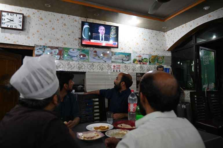 People watch a television in a restaurant as Pakistan's Prime Minister Shehbaz Sharif addresses the nation, in Islamabad on May 7, 2025. India and Pakistan exchanged heavy artillery along their contested frontier on May 7, after New Delhi launched deadly missile strikes on its arch-rival in the worst violence between the nuclear-armed neighbours in two decades. (Photo by Aamir QURESHI / AFP)