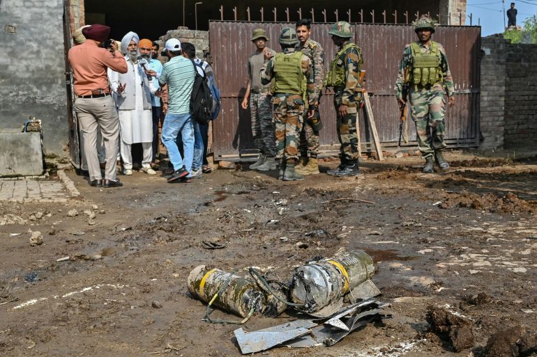 Indian army personnel stand next to explosives, carried by a drone, after it was intercepted by the Indian air defence system, on the outskirts of Amritsar, on May 10, 2025. The Indian army on May 10 reported fresh Pakistani attacks along the border with its arch-foe as the conflict between the nuclear-armed neighbours spiralled. (Photo by Narinder NANU / AFP)