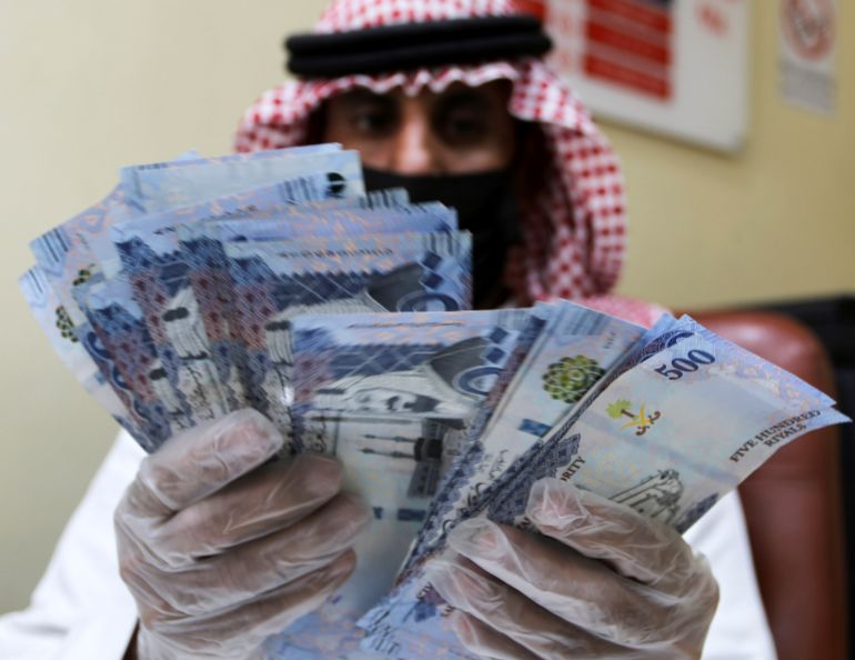 A Saudi money exchanger wears gloves as he counts Saudi riyal currency at a currency exchange shop in Riyadh