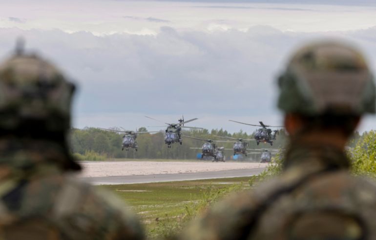 Soldiers look at German Air Force helicopters taking off at the airfield of Pajuostis in Panevezis, Lithuania on May 6, 2025, during the „Griffin Lightning 2025“ military exercises.