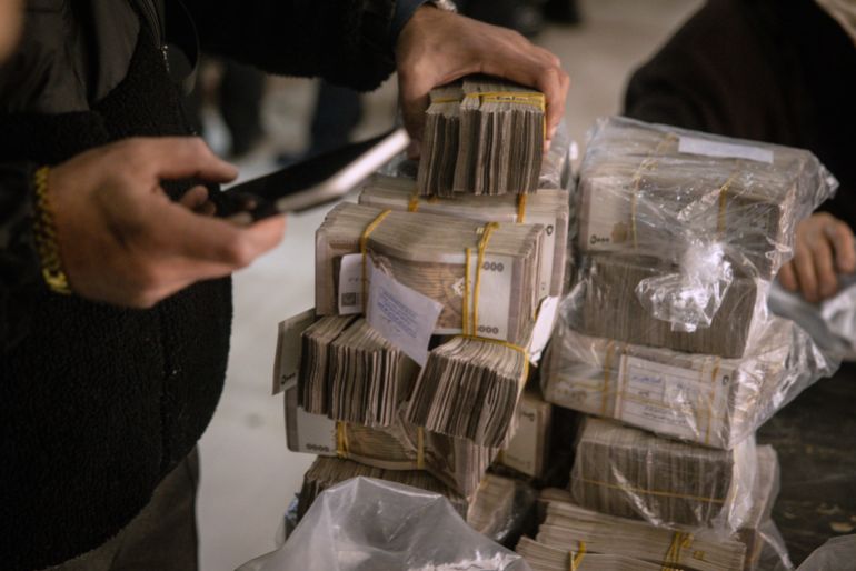 DAMASCUS, SYRIA - DECEMBER 24: A man counts stacks of Syrian pounds after exchanging U.S dollars at the Central Bank Of Syria on December 24, 2024 in Damascus, Syria. On December 8, rebel forces in Syria retook the capital and several other cities from longtime ruler Bashar al-Assad, who fled the country for Moscow. The fall of the Assad regime marks a new chapter for Syria, which has been mired in a multi-party civil war since 2011, sparked by the Arab Spring uprisings. (Photo by Chris McGrath/Getty Images)