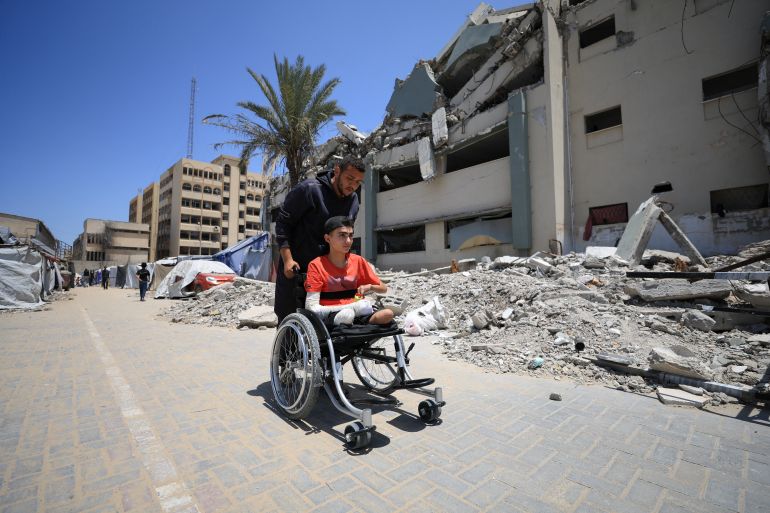 A Palestinian man pushes Ahmad Al-Ghalban, a 16-year-old Palestinian gymnast, who lost both his legs in an Israeli airstrike on Beit Lahiya, as he sits in his wheelchair, in Gaza City, May 21, 2025. REUTERS/Dawoud Abu Alkas