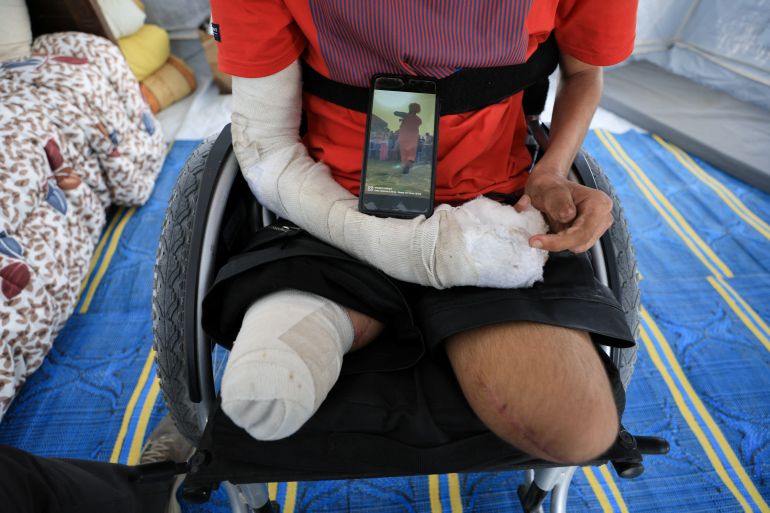 Ahmad Al-Ghalban, a 16-year-old Palestinian gymnast, who lost both his legs in an Israeli airstrike on Beit Lahiya, sits in his wheelchair as he shows his photo on a mobile phone, inside the tent where he took shelter after being displaced, in Gaza City, May 21, 2025. REUTERS/Dawoud Abu Alkas