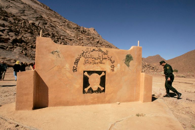 A military police walks at the French nuclear tests' site in In-Ekker near Ain Maguel, 170 km (106 miles) from the southern Algerian town of Tamanrasset, February 16, 2007. France should apologise for atom bomb tests in its former colony Algeria which were an atrocious crime that harmed humans and the environment, an Algerian official said on Tuesday.The Arabic script reads: "Nuclear tests site of the former French colony from 1960 to 1967 in Taorirt mountain in In-Ekker near Ain Maguel." Picture taken February 16, 2007. REUTERS/Zohra Bensemra (ALGERIA)