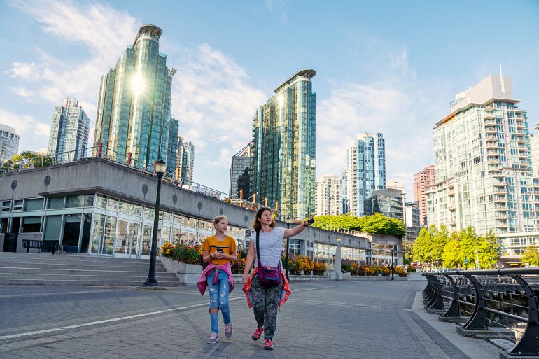 Mother and daughter walk along the Coal Harbor in Vancouver downtown, Canada