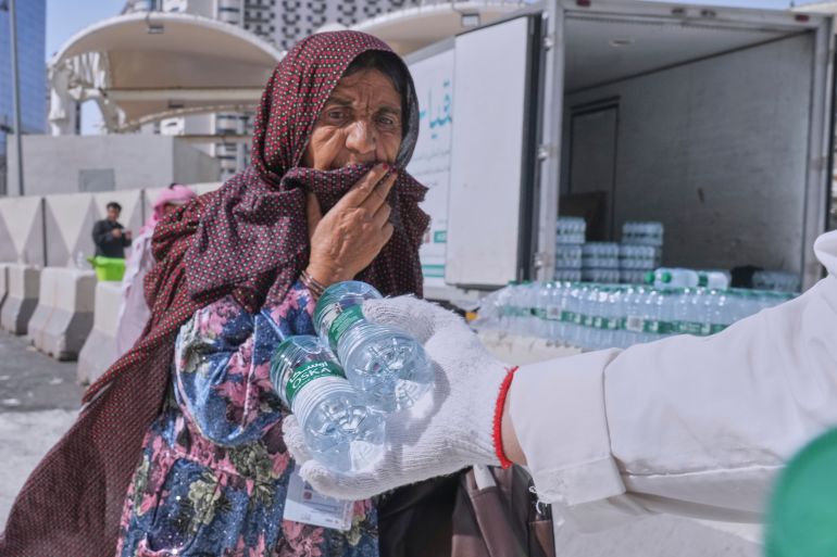 A worker distributes free Zamzam water, water from the holy well of Zamzam, to a pilgrim outside the Grand Mosque, during the annual hajj pilgrimage, at the holy city of Mecca, Saudi Arabia, Tuesday, June 3, 2025. (AP Photo/Amr Nabil)