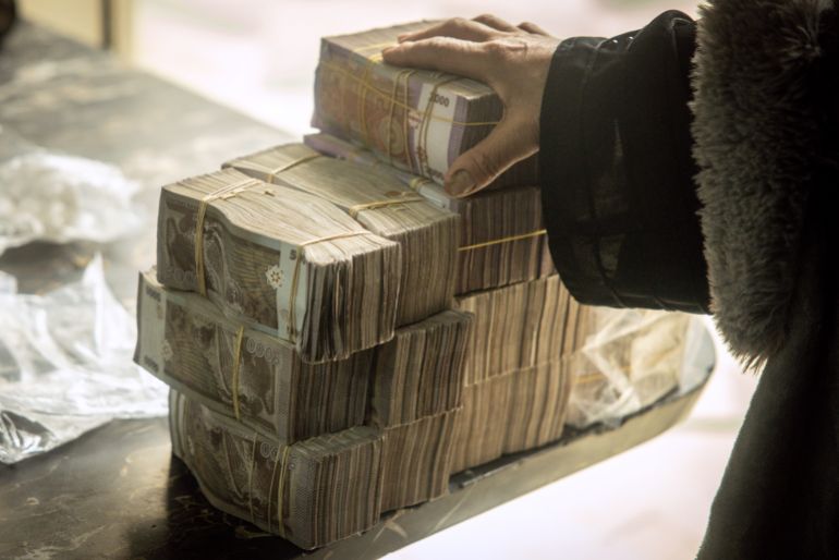 DAMASCUS, SYRIA - DECEMBER 24: A woman holds a stack of Syrian pounds after exchanging U.S dollars at the Central Bank Of Syria on December 24, 2024 in Damascus, Syria. On December 8, rebel forces in Syria retook the capital and several other cities from longtime ruler Bashar al-Assad, who fled the country for Moscow. The fall of the Assad regime marks a new chapter for Syria, which has been mired in a multi-party civil war since 2011, sparked by the Arab Spring uprisings. (Photo by Chris McGrath/Getty Images)
