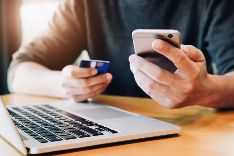 Online payment,Young Man's hands holding smartphone and using credit card and computer laptop for online shopping. black friday or cyber monday concept. shutterstock_1045631839