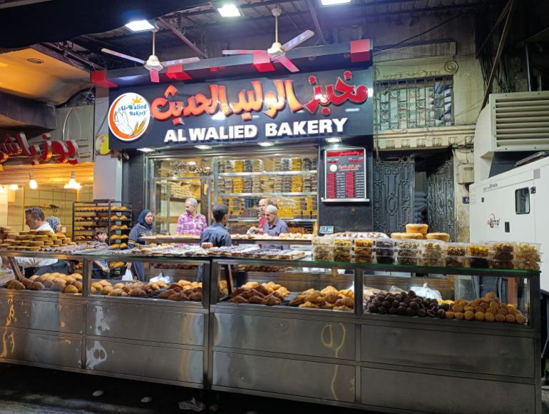 في الصباح، تستفيق البيوت على أصوات الباعة وروائح الخبز، كأن الحي يتنفس حياة دمشق (الجزيرة)