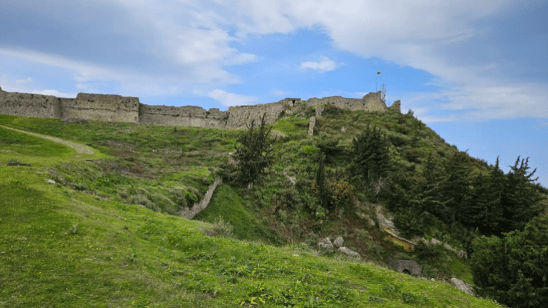على تل ثلاثي القمم جنوب مدينة فلورا تقع قلعة كانينا لتكون نقطة التقاء بين عراقة التاريخ وسحر الطبيعة