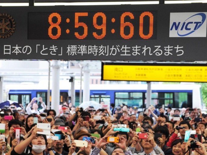 People looks up a clock board which shows the time of 8:59:60, between 8:59:59 and 9:00:00 for a leap second in Tokyo on July 1, 2015. Japan inserted a leap second to adjust the gap between the Earth's rotation and atomic clocks. This will be the first addition of a leap second in three years. AFP PHOTO / JIJI PRESS JAPAN OUT