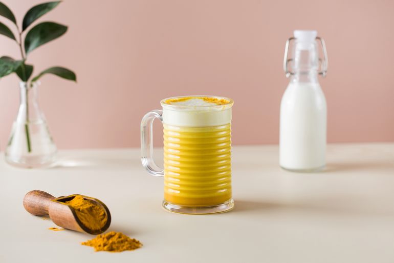 Latte turmeric on a pink background. Moon milk for better sleep. Ayurvedic drink. Copy space. High quality photo