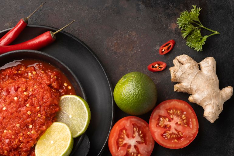 A top view of a delicious sambal arrangement with different fruits and vegetables on a dark background