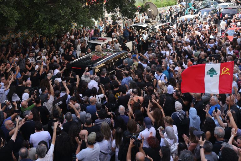 Mourner wave a banner combining the Lebanese and Communist Party flags as they gather around the hearse of renowned Lebanese musician and composer Ziad Rahbani outside Khoury Hospital in Beirut's central Hamra district on July 28, 2025.