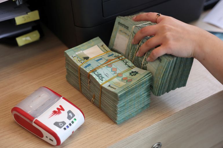 A person at Whish Money, Fintech and Digital money transfer company, holds Lebanese pound banknotes inside a branch in Beirut, Lebanon June 11, 2025. REUTERS/Mohamed Azakir