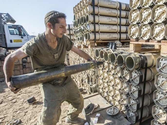 An Israeli soldier carries a shell as he and his comrades prepare their Merkava tanks stationed at an army deployment area along the border between Israel and the Hamas-controlled Gaza Strip on July 31, 2014. Israel mobilised 16,000 additional reservists today to bolster forces fighting in Gaza as Washington gave its ally the go-ahead to raid stocks of emergency US weapons stored on Israeli soil. AFP PHOTO/JACK GUEZ