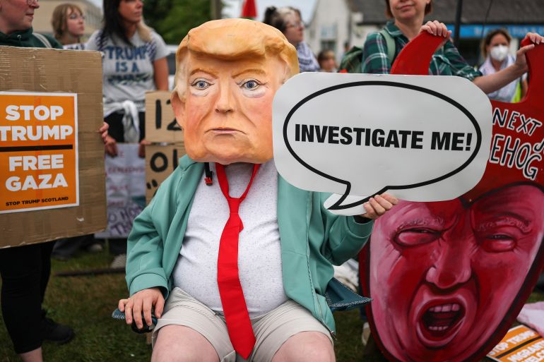 BALMEDIE, SCOTLAND - JULY 28: A person dressed as Donald Trump holds a sign saying 'Investigate me' as demonstrators protest against the visit of President Trump’s visit to his golf course at Balmedie on July 28, 2025 in Aberdeen, Scotland. U.S. President Donald Trump is visiting his Trump Turnberry golf course, as well as Trump International Golf Links in Aberdeenshire, during a brief visit to Scotland from July 25 to 29. (Photo by Jeff J Mitchell/Getty Images)