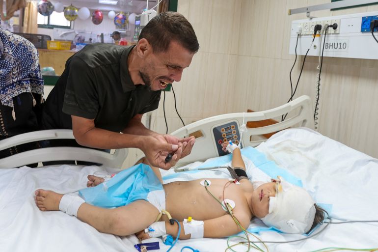 Palestinian father Hatem Al-Nouri, who lost two of his children, Omar and Amir, in the July 10 Israeli strike while they were queuing for supplements near a medical center, reacts as he accompanies his son Siraj, who was wounded in the same strike, at Al-Aqsa Martyrs Hospital in Deir al-Balah, in the central Gaza Strip, July 14, 2025. REUTERS/Ramadan Abed